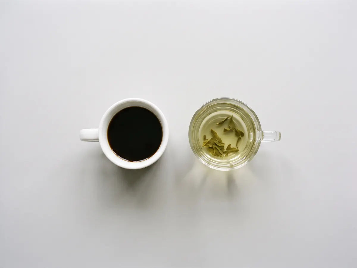 A cup of black coffee next to a glass cup of green tea